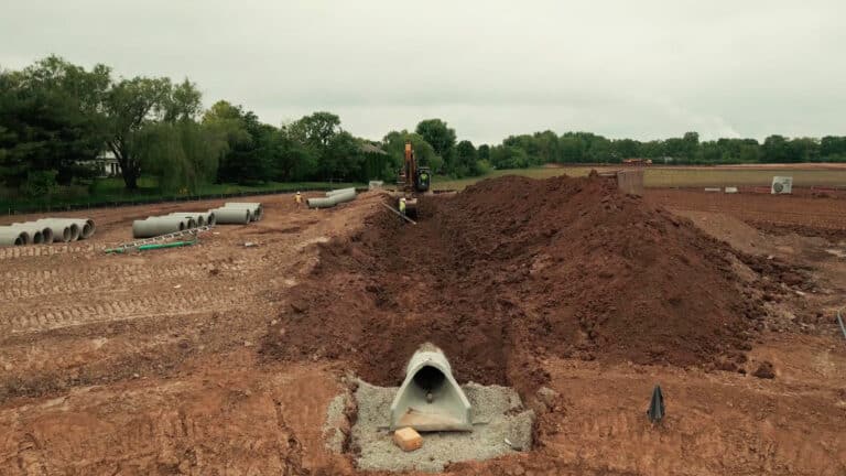 Storm pipe installation underway at Lebanon construction site with excavator and crew.